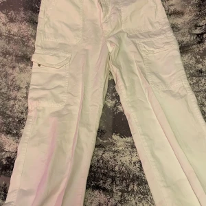 Jeans Vit Cargo-fickor   - Byxan är vit lång har två knappar så man kan stänga fickorna 