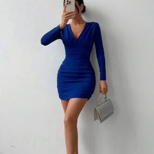 Blå klänning med v-ringning - Säljer en snygg blå klänning med v-ringning och långa ärmar. Den är tight och ganska kort, perfekt för festliga tillfällen. Klänningen har en stilren design och är gjord i ett mjukt material som sitter bekvämt på kroppen. Använd 1 gång.