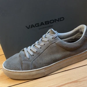 Grå sneakers från Vagabond - Säljer ett par snygga grå sneakers från Vagabond. De är gjorda i mocka och har en stilren design med snörning. Perfekta för både vardag och fest. Skorna är i bra skick och har en bekväm passform.