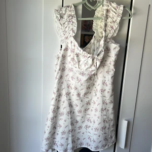 Blommig klänning - Vit och lila. Köpte från Cider men passade inte. Prislapp kvar. Väldigt bra skick. Knyte vid bysten