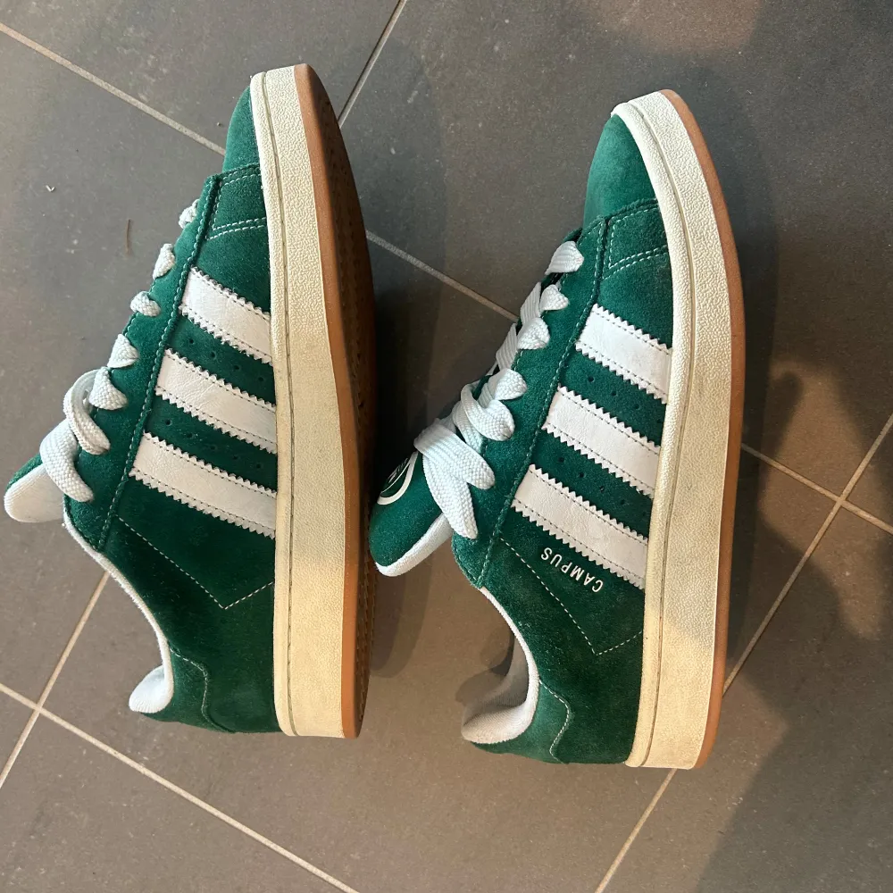 Ett par Adidas Campus 00 i ”Dark Green” i storlek 42. Väl omhändertagna och i bra skick! Finns en wear-slitning i vänster innersko men påverkar inget överhuvudtaget! Är lätt ett utav dom bekvämaste skorna jag ägt! Box medföljer + gröna skosnören. Skor.