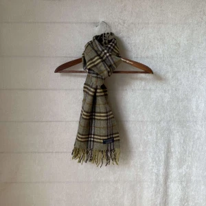 burberry halsduk - Säljer en burberry halsduk i färgen mörk grön. Den är gjord av 100% lammull mjuk. Perfekt för att hålla sig varm under höst och vinter. En tidlös accessoar som passar till alla outfits! Skicket på denna är 9/10 och är såklart äkta 👍 vid frågor är det bara att höra av sig👍