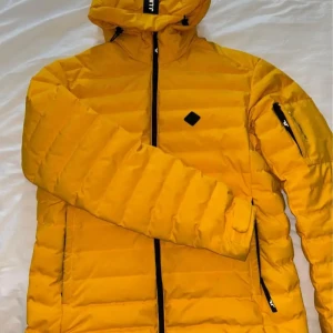 J Lindeberg, vinterjacka / skidjacka  knappast använd. Vattentät & vindtät. Nypris 5700:- - J Lindeberg från säsongen 2023 Använd mycket sällan.   Wind & waterproof ✅ Vattentät med fluorkolfri DWR-beläggning-  Högkvalitativ dun- 90/10 dun/fjäder,  700 fyllkraft  Spårbart dun av högsta kvalitet 90/10 700 FP  Nypris är 5700:-   Hör av 