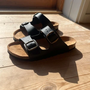 Svarta sandaler från Race Marine - Säljer ett par svarta sandaler från Race Marine. Är exakt likadana som Birken Stok! De har två justerbara remmar med spännen och en bekväm sula som inte är nedtrampad.  St 39. Kartong + kvitto. Köpte nya för 380 kr. Små i storleken!! Är egentligen 38