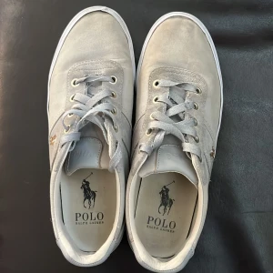 Grå sneakers från Polo Ralph Lauren - Säljer ett par ralph lauren skor som är 100% äkta dem är i bra skick. Säljer skorna för att jag har vuxit ur mig dem. Ny pris är över 1200 kr