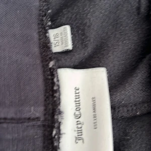 Svarta byxor från Juicy Couture - Säljer ett par svarta byxor från Juicy Couture. De är gjorda i ett mjukt material och har snygga detaljer som broderad logga och fickor med knappar. Perfekta för en avslappnad men stilren look!