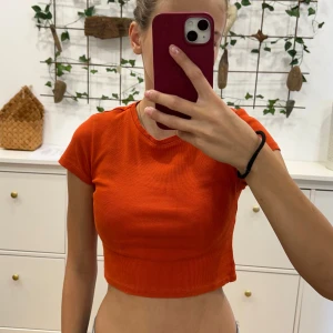 Röd ribbad t-shirt - En fin ribbad t-shirt med orange/röd färg. Köpt från New Yorker i storlek S men den är väldigt kroppad (jag är 170). Tröjan har lite slitage längst med sömmen så priset är diskuterbart!😊😊