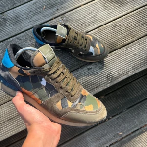 Valentino rockrunners  - Säljer ett par feta camo rockrunners med blå detalj på hälen. Dom är i okej skick och ingen låda, därav det billiga priset. Funkar både t vardag o fest. Tveka inte på att ställa frågor🙌🙌