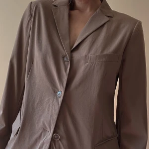 Vintage Jil Sander Blazer - Chic 90s style Vintage Jil Sander Woven Brown Blazer. Made in Italy. Woven Fabric has a slight stretch. Features 1 Chest Pocket & 2 Side Pockets. 3 Button Closure. Very Good Condition. Original Tagged Size 40, Model is 160CM