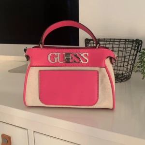 Fin väska från Guess - Rosa,vit med nitar och guld textad Använd 1 ggr Köpt på Jackie i Sthlm 