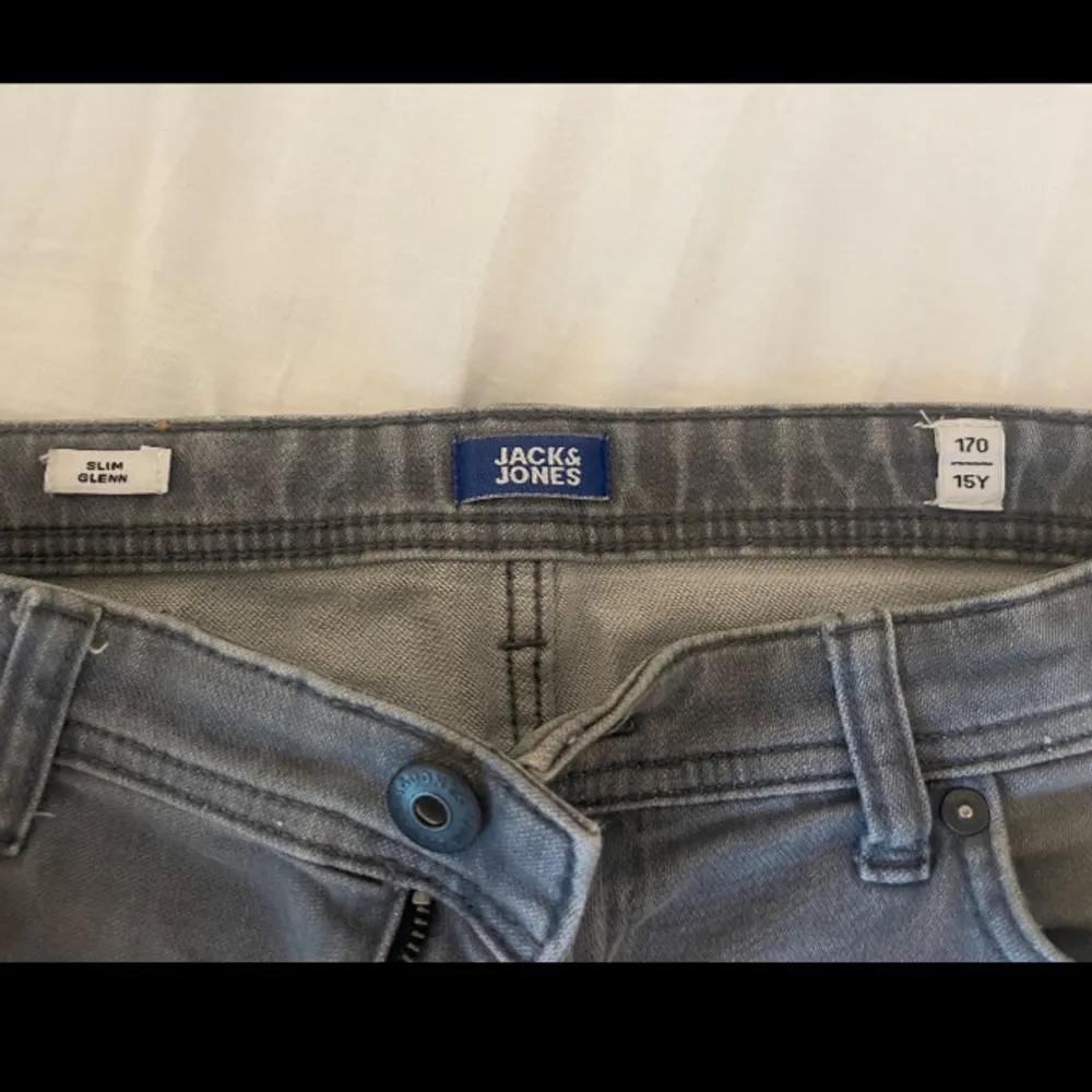 Slim Glenn jeans från Jack and Jones. Grå färg. Storlek 170 för 15 åringar. Använda i kanske 4 månader men sluta använda pga hade för stora lår. Går att diskutera priset och fråga gärna om mer bilder om ni undrar.. Jeans & Byxor.