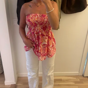 Färgglad axelbandslös topp - Säljer en superfin axelbandslös topp .Toppen har ett smockat liv som ger en tight passform upptill och en luftigare känsla nedtill. Perfekt för sommardagar eller en festlig kväll!