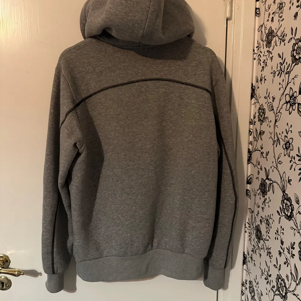 Säljer en grå hoodie från Trapstar med stor logga i vitt och svart på bröstet. Den är superbekväm och perfekt för chill dagar. Hoodien har en klassisk känguruficka och justerbar huva. Perfekt för höst och vinter! byxorna ingår . Tröjor & Koftor.