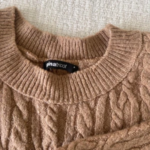 Beige stickad tröja från Gina Tricot - Säljer en supermysig beige stickad tröja från Gina Tricot. Den har ett snyggt flätmönster och ribbade muddar vid ärmslut och hals. Perfekt för höst och vinter när du vill hålla dig varm och stilren. Passar till både jeans och kjol!