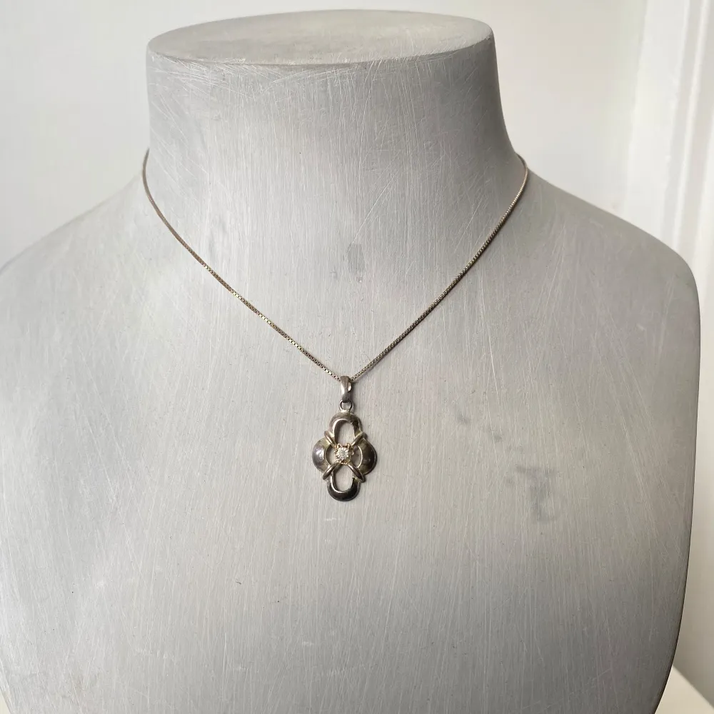 Säljer ett elegant silverhalsband med ett unikt blomformat hängsmycke. Hängsmycket har en vacker design med en glittrande sten i mitten som ger en extra touch av glamour. Perfekt för både vardag och fest! stämplat 925. Asusteet.