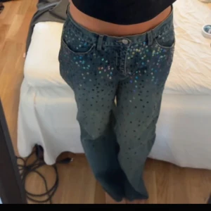 Blå jeans med paljetter - Ett par blå jeans med paljetter på framsidan. Jeansen har en rak passform och är midwaist.