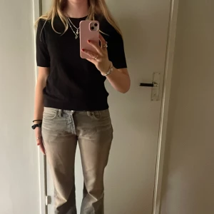 Svart tröja från H&M - Säljer en stilren svart stickad T-shirt från H&M. Tröjan har korta ärmar och är perfekt för både vardag och fest. Den är i väldigt bra skick och passar till det mesta i garderoben. Perfekt för höst och vår!