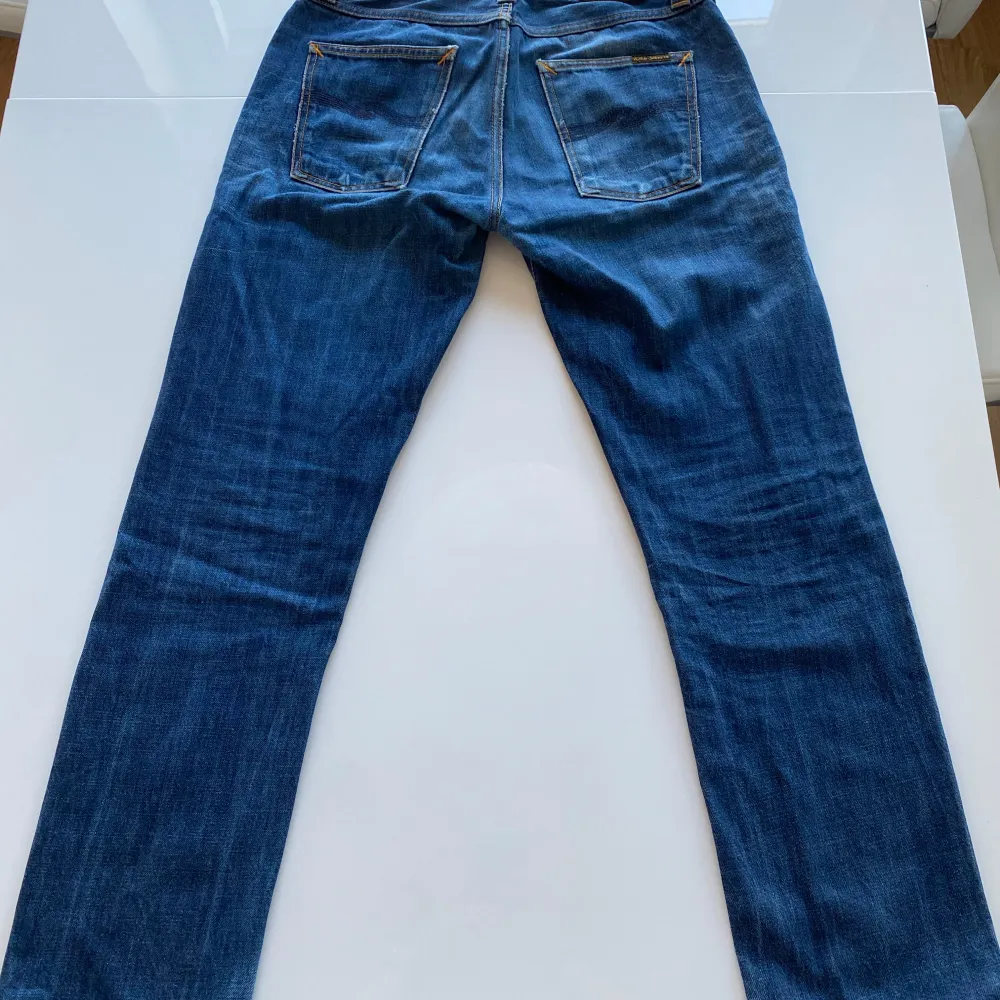 Säljer ett par klassiska blå jeans från Nudie Jeans Co i storlek W30 L32. De har en snygg, sliten look med orange sömmar. Dessa är uppsydda någon cm i benen därav de låga priset. Perfekta till skolan eller på stan! Tveka inte på att kontakta mig om frågor skulle uppstå!. Jeans & Byxor.