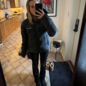 Svart dunjacka från Sail Racing - Säljer en svart dunjacka från Sail Racing. Den är supervarm och perfekt för kalla vinterdagar. Jackan har en dragkedja framtill och långa ärmar. Den är i bra skick och passar perfekt för både vardag och utomhusaktiviteter.