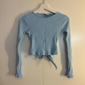Topp med knyte i ryggen - Fin blå ribbad tröja med knyte i ryggen, från Newyorker, strl S. Fint skick, använd nån gång. 40 kr + frakt🌟