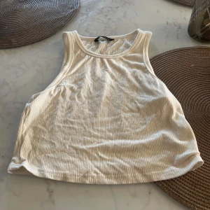 Vit ribbad linnetopp från SHEIN - Säljer en superfin vit ribbad linnetopp från SHEIN i storlek XS. Perfekt för sommardagar eller som ett basplagg i garderoben. Toppen är ärmlös och har en bekväm passform. Använd den som den är eller under en snygg jacka!