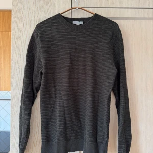 Mörkgrön stickad tröja från COS - Säljer en snygg mörkgrön stickad tröja från COS i storlek S. Perfekt för höst och vinter med sin mysiga och varma känsla. Tröjan har en klassisk rund hals och långa ärmar. Den är i nyskick och gjord av 100% bomull, vilket gör den både bekväm och hållbar. Passar perfekt till både vardag och fest!