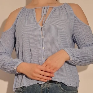 Blårandig blus med öppna axlar - Blårandig blus med bara axlar samt kmyte och knappar fram.  (Sista bilden visar tröjans material)