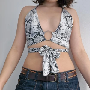 Ormmönstrad bikini från PrettyLittleThing - Säljer en supercool ormmönstrad halternecktopp från PrettyLittleThing i storlek S. Den har en snygg v-ringad design med en ringdetalj framtill och knytband. Helt ny, perfekt för fest! 