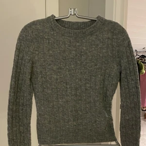 Grå stickad tröja från BikBok! XS - Säljer en mysig grå stickad tröja från BikBok i ullblandning. Tröjan har ett klassiskt flätmönster och långa ärmar, perfekt för kyliga dagar. Den har en ribbad kant vid ärmslut och nederkant för extra komfort. Passar perfekt till höst- och vintergarderoben.