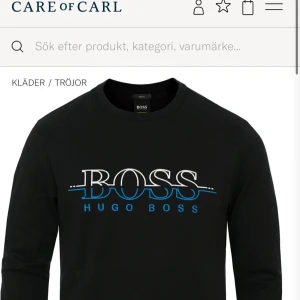 Svart tröja från Hugo Boss - Snygg svart tröja från Hugo Boss med ett stort BOSS-tryck i vitt och blått på bröstet. Bra skick. Storlek L men liten i storleken. Säljs inte längre + nypris på den ca 1400kr
