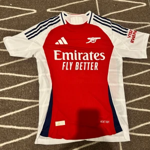  Arsenal fotbollströja 24/25  - Säljer en snygg Arsenal fotbollströja, den har  Saka på ryggen och nummer 7 .  Nyskick