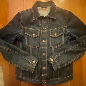 Jeansjacka från Nudie Jeans - Snygg Nudie jeans jeansjacka ”Billy Dry Super Blir” i M. Jackan är i fint skick och sparsamt använd. Perfekt till våren! Nypris för jackan är runt 3000kr! Kontakta vid eventuella frågor!