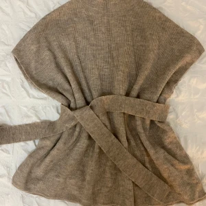 Beige ribbad tröja från Kappahl - Säljer en stilren beige ribbad tröja från Kappahl. Tröjan har ett bälte i midjan för en snygg passform och är perfekt för kyligare dagar. Den är i en one size-storlek och passar de flesta. Perfekt för att hålla sig varm och trendig!