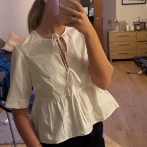 Vit blus från H&M  - Säljer en söt vit blus från H&M. Blusen har korta ärmar och en knytning framtill som ger en fin detalj. Helt ny och aldrig använd, endast testad.