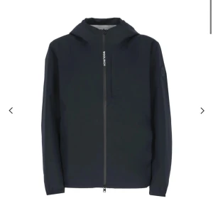 Woolrich jacka - Snygg regnjacka från Woolrich med huva och dragkedja framtill. Jackan har en stilren design med en diskret logotyp på ärmen. Perfekt för blåsiga och regniga dagar och ger en cool look. Endast använd en gång så 10/10 skick