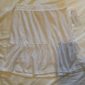 Vit kjol från Bubbleroom - Säljer en söt vit kjol från Bubbleroom med broderade detaljer. Kjolen har en volangkant och är perfekt för varma dagar. Den är tillverkad i ett lätt och luftigt material som ger en romantisk känsla. Passar perfekt för sommarens alla tillfällen. 🌸 Kjolen är aldrig använd.