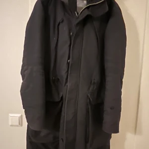 Svart parkajacka från G-Star Women - Säljer en stilren svart parkajacka från G-Star Women. Jackan har en praktisk huva och dragkedja framtill. Perfekt för kyligare dagar med sin långa design och bekväma passform.                                                                Finare i verklighet,ej uttvättat som det ser ut på bilden 
