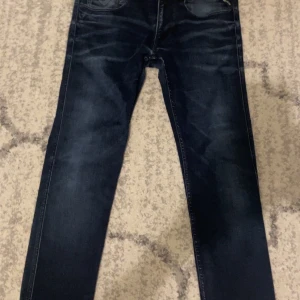 Mörkblå Replay anbass jeans - Snygga mörkblå jeans från Replay i modellen Anbass. De har en klassisk femficksdesign och en knappgylf. Perfekta för en stilren look.