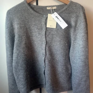 Grå kofta från Gina Tricot - Säljer en stilren grå kofta från Gina Tricot i premiumkvalitet. Koftan har en rund halsringning och knappar framtill. Perfekt för kyligare dagar. XL men sitter som M, riktigt fin passform.