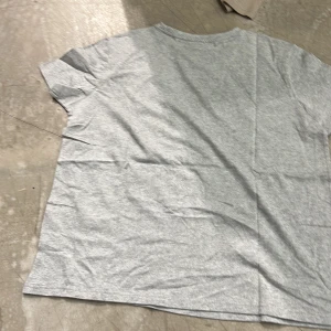 Grå t-shirt - En enkel och stilren grå t-shirt i bomull. Perfekt för en avslappnad look. T-shirten har korta ärmar och en normal passform.