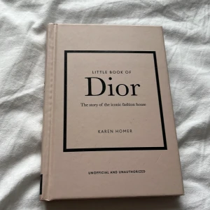 Little Book of Dior - Utforska historien om det ikoniska modehuset Dior i denna bok av Karen Homer. Boken erbjuder en djupdykning i Diors liv och arv, med vackra illustrationer och insiktsfull text. Perfekt för modeentusiaster och de som älskar lyx och elegans.