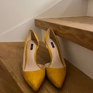 Gula pumps från Mango - Snygga gula pumps från Mango med spetsig tå och klack. Perfekta för att lysa upp din outfit med en färgklick.