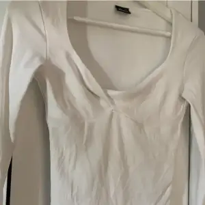 Säljer en stilren vit långärmad topp från Gina tricot med v-ringad.  Passar till många olika outfits! Har ett litet hål inne i tröjan men syns inte