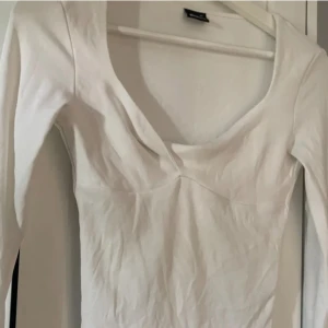 Vit långärmad topp  - Säljer en stilren vit långärmad topp från Gina tricot med v-ringad.  Passar till många olika outfits! Har ett litet hål inne i tröjan men syns inte