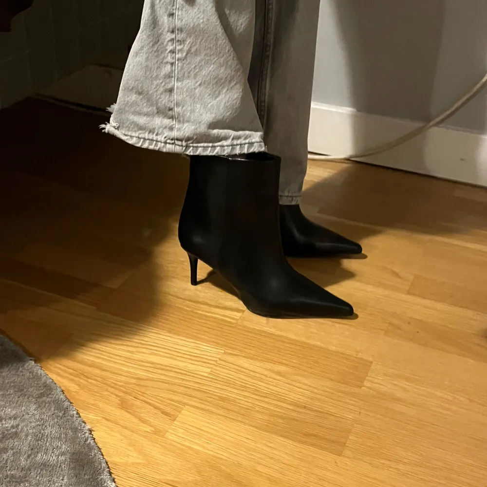 Snygga svarta boots med spetsig tå och klack. Perfekta för en stilren look. De är tillverkade i ett slätt material och har en elegant design. Aldrig använda . Kengät.