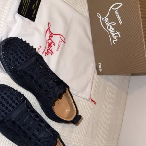 Mörkblå skor från Christian Louboutin  - Loubs från Christian Louboutin med ikoniska röda sulor och nitar på ovansidan. Skorna har snörning och är tillverkade i skinn, vilket ger en lyxig känsla. Perfekta för att ge en edgy touch till din stil. Helt nya i kartong ingår kartong och dustbag .