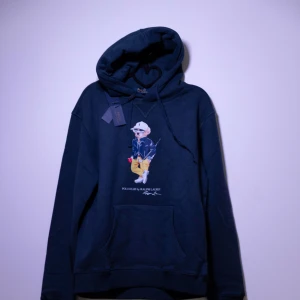 Ralph Lauren Hoodie - Helt ny Ralph Lauren Hoodie med en ikonisk nallebrodyr på framsidan. Hoodien har en klassisk passform med justerbar huva och en praktisk magficka. Perfekt för en avslappnad stil. Fler storlekar finns i min profil😊