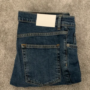 Blå jeans från Taktill - Snygga blå jeans från Taktill i modellen William Tapered. De har en klassisk femficksdesign med dragkedja och knapp framtill. Perfekta för en avslappnad stil. Jag har haft dom på mig en gång. Skick 10/10