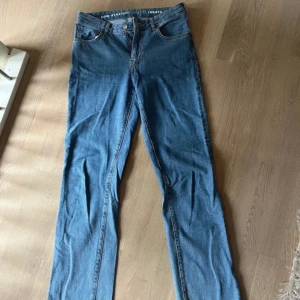 Blå jeans med låg midja - Snygga blå jeans med låg midja och rak passform. Perfekta för en avslappnad stil. De har klassisk femficksdesign och stängs med dragkedja och knapp.