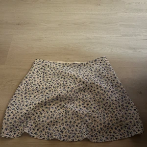 Blommig jättefin kjol  - Säljer den här jättefina kjolen med en dragkedja på sidan då den aldrig kommer till användning pga den är för stor för mig. Den är från Hm och använd ett fåtal gånger. 